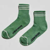 Green socks with striped cuffs and 'Le Bon Shoppe' branding on a light gray background