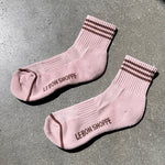 Pink socks with brown stripes with Le Bon Shop branding on concrete floor
