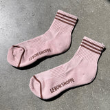 Pink socks with brown stripes with Le Bon Shop branding on concrete floor