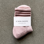 Pink socks with brown stripes in white Le Bon Shoppe packaging on concrete floor