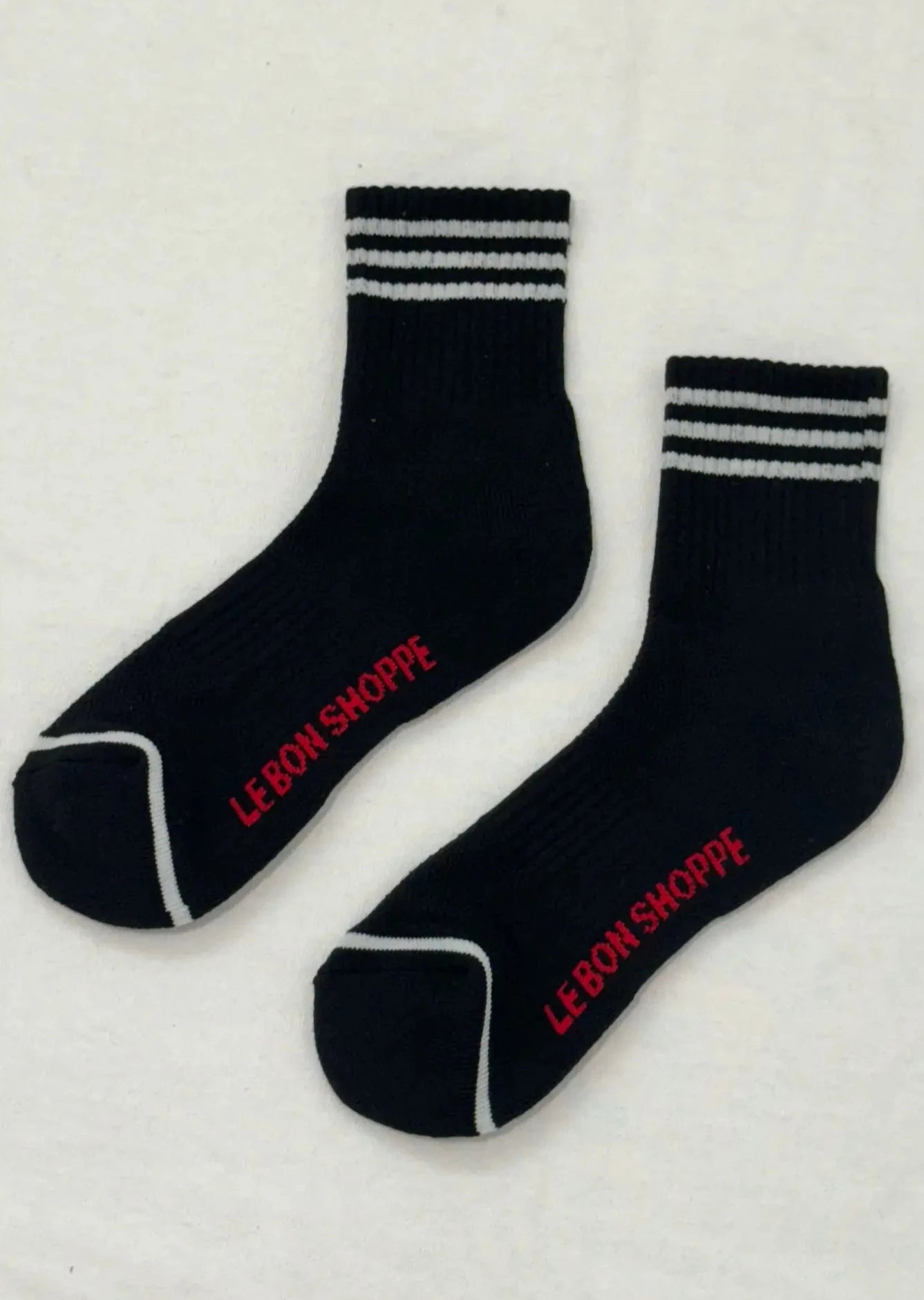 Black socks with white stripes and red Le Bon Shoppe branding on white background