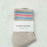 Gray sock with colorful stripes and 'Le Bon Shoppe' label on a light gray background