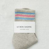 Gray sock with colorful stripes and 'Le Bon Shoppe' label on a light gray background