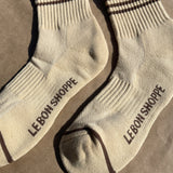 Yellow socks with brown stripes and Le Bon Shoppe branding with kraft paper background