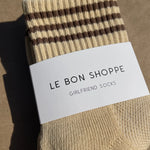 Yellow socks with brown stripes in white Le Bon Shoppe packaging with kraft paper background