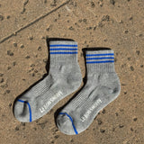 Grey socks with blue stripes laying on a concrete floor