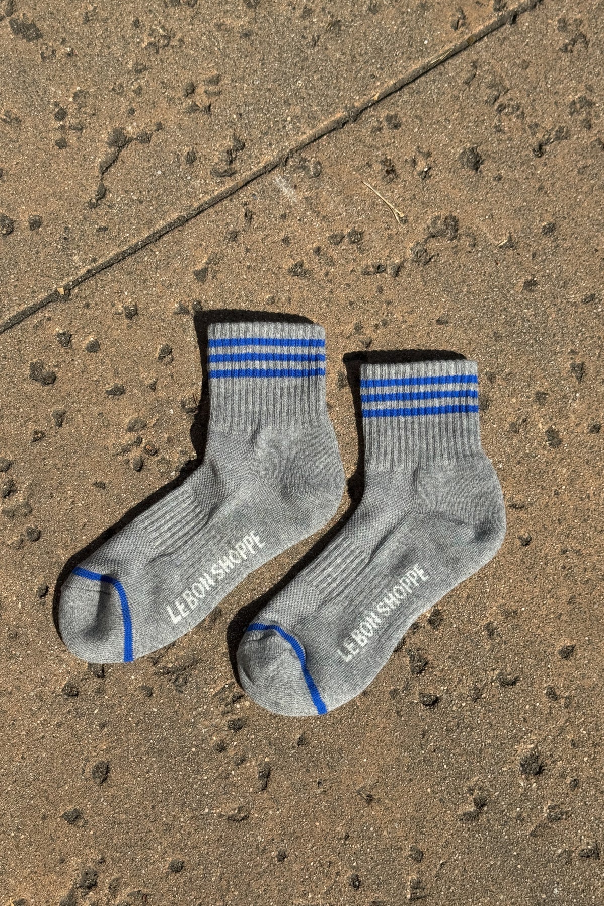 Grey socks with blue stripes laying on a concrete floor