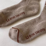 Pair of brown socks with 'Le Bon Shoppe' branding on a light background