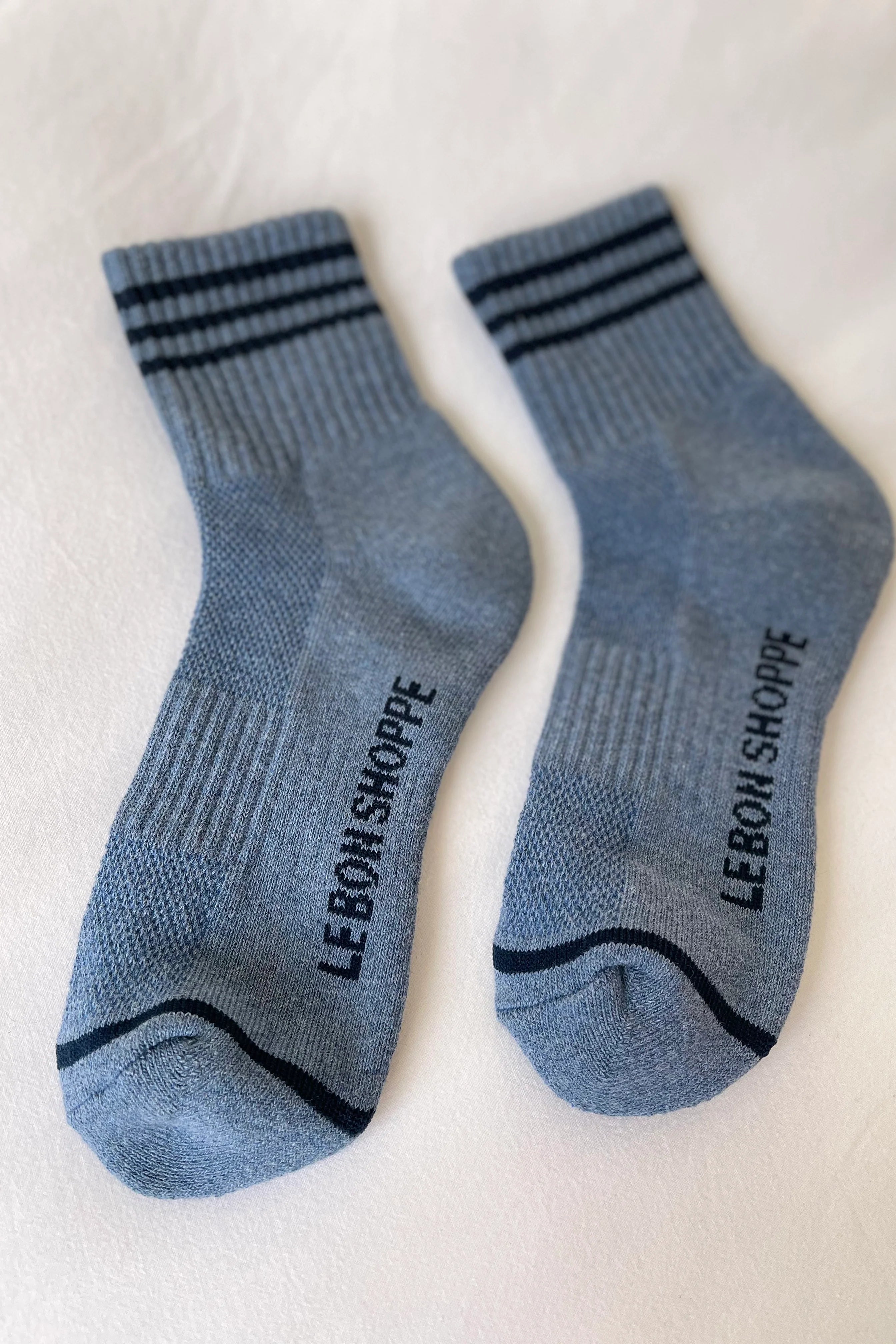 Blue socks with navy stripes and Le Bon Shoppe branding on white background