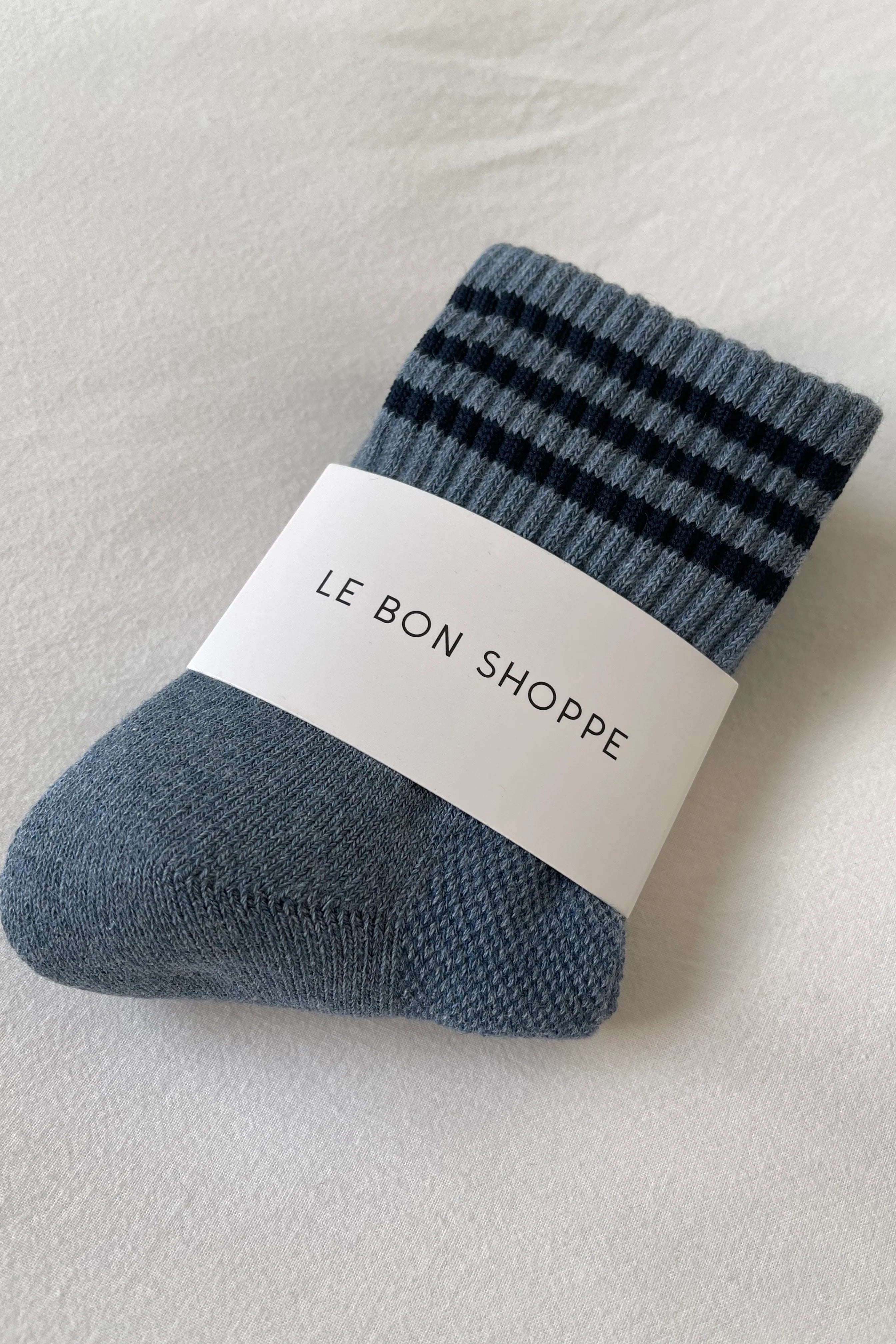 Blue shoes with navy stripes in white Le Bon Shoppe packaging on white background
