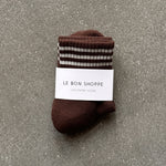 Brown socks with white stripes in white Le Bon Shoppe packaging on concrete floor