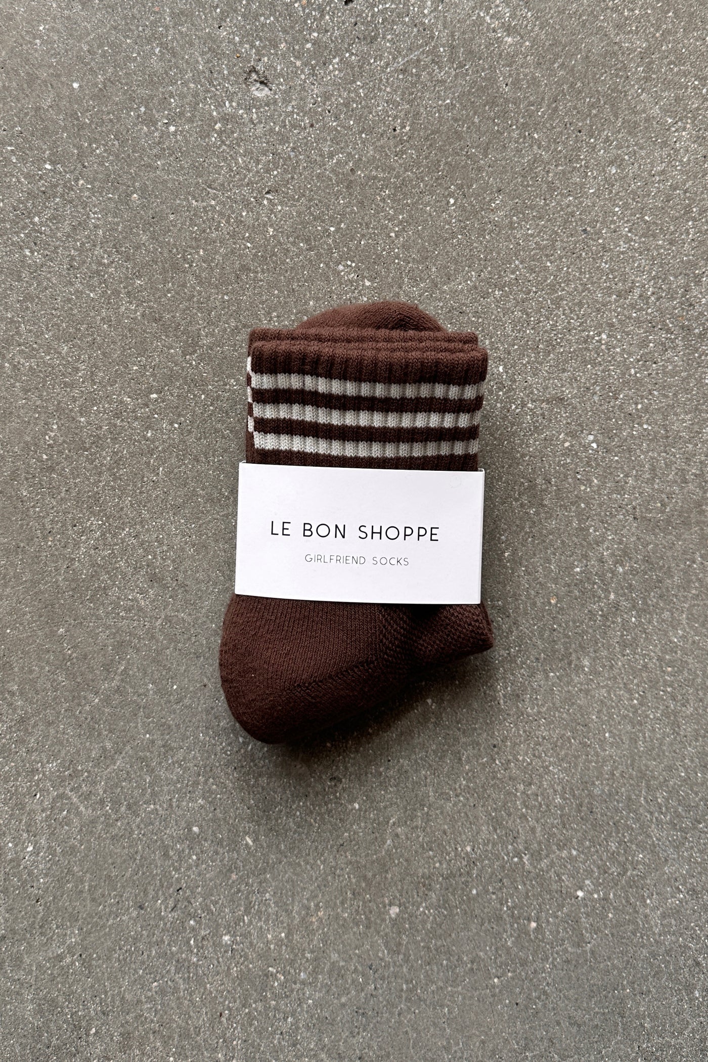 Brown socks with white stripes in white Le Bon Shoppe packaging on concrete floor