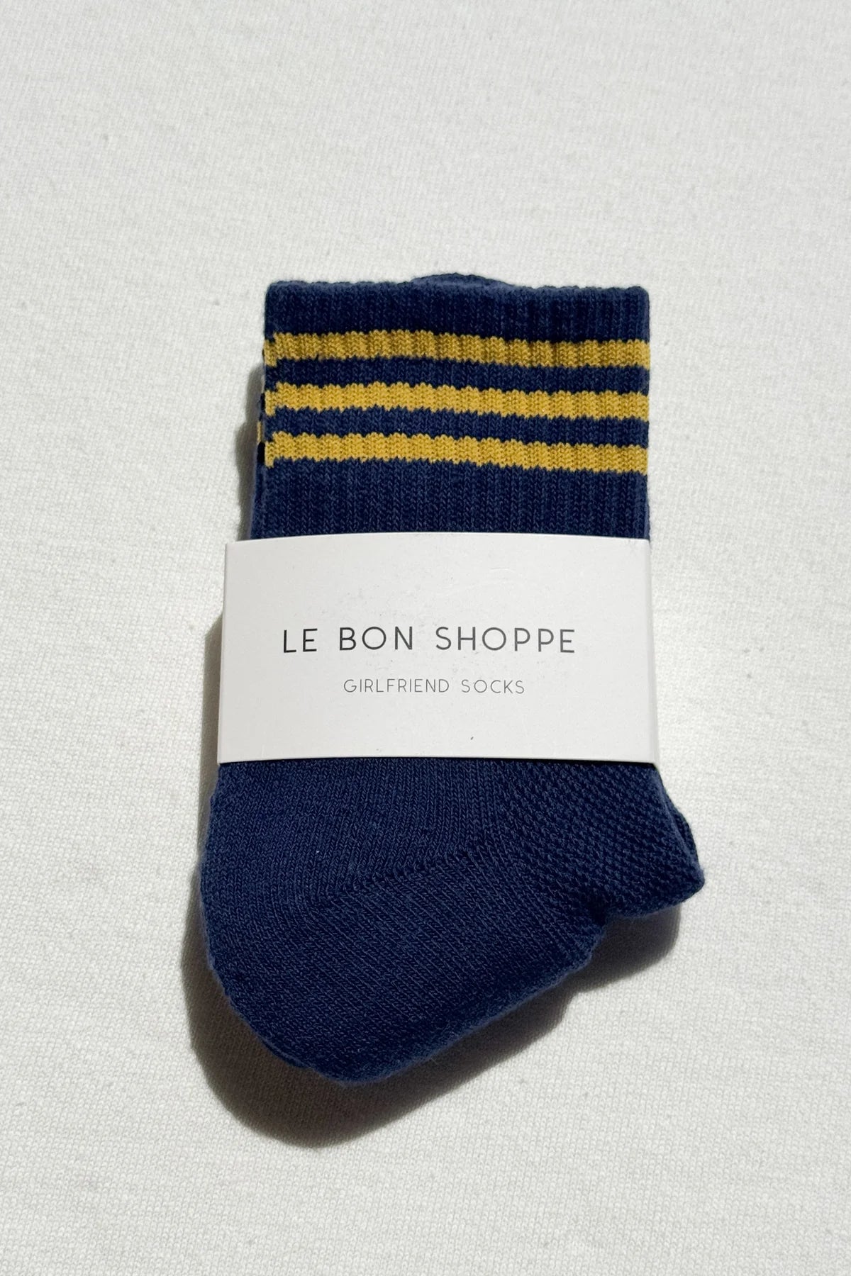Pair of blue socks with yellow stripes and a visible brand label on a light gray background
