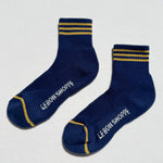 Pair of blue socks with yellow stripes and 'Le Bon Shoppe' branding on a white background