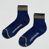 Pair of blue socks with yellow stripes and 'Le Bon Shoppe' branding on a white background
