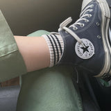 Person wearing navy Converse shoes with white soles sitting inside a vehicle.