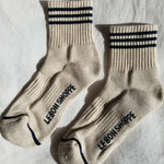 Pair of beige socks with black stripes and text on a light gray background
