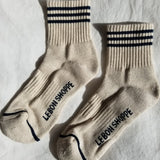 Pair of beige socks with black stripes and text on a light gray background