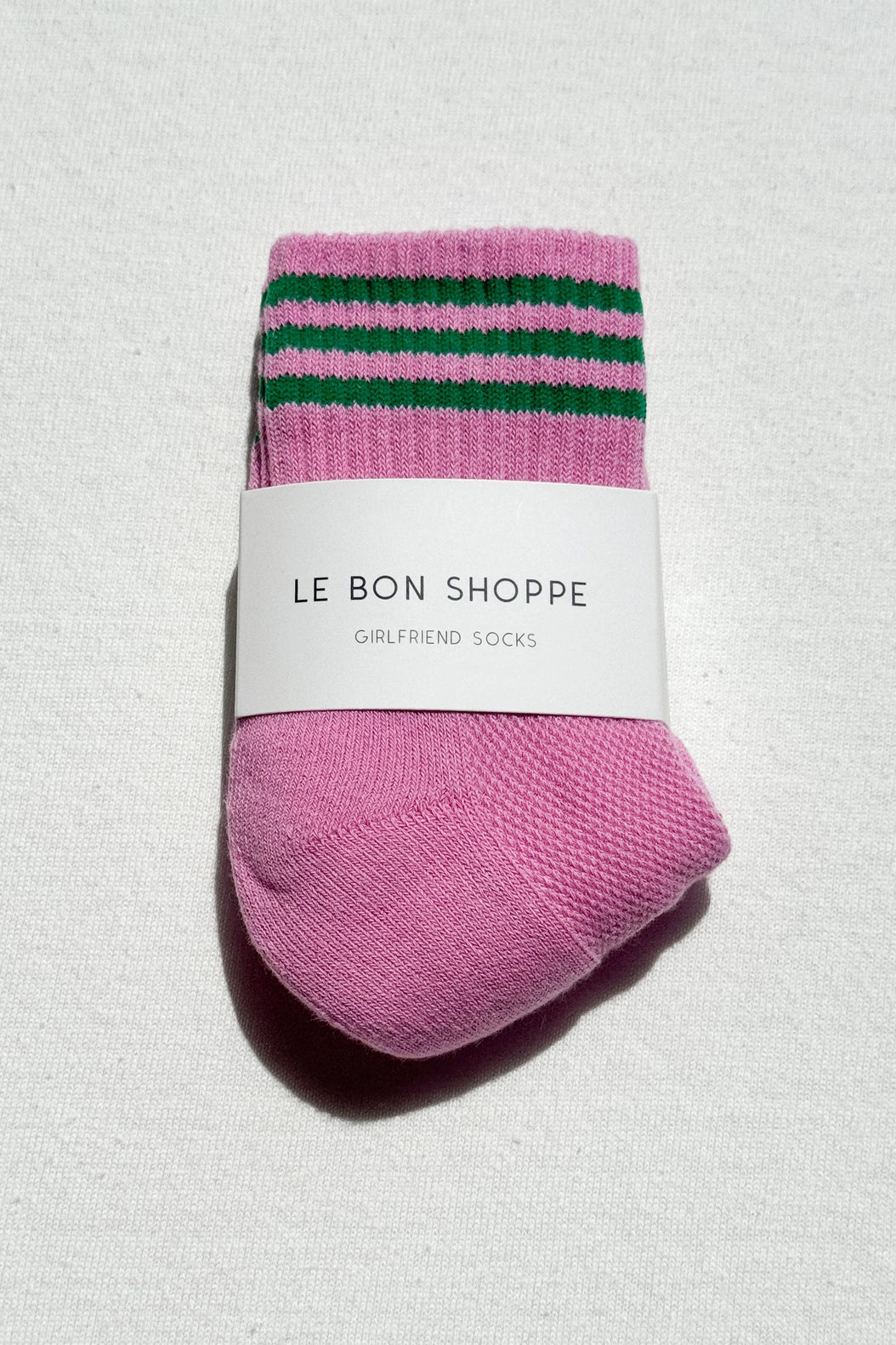 Pink socks with green stripes on a white background, labeled 'Le Bon Shoppe'.