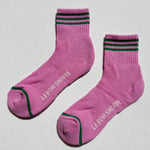 Pink socks with black and green accents on a light gray background