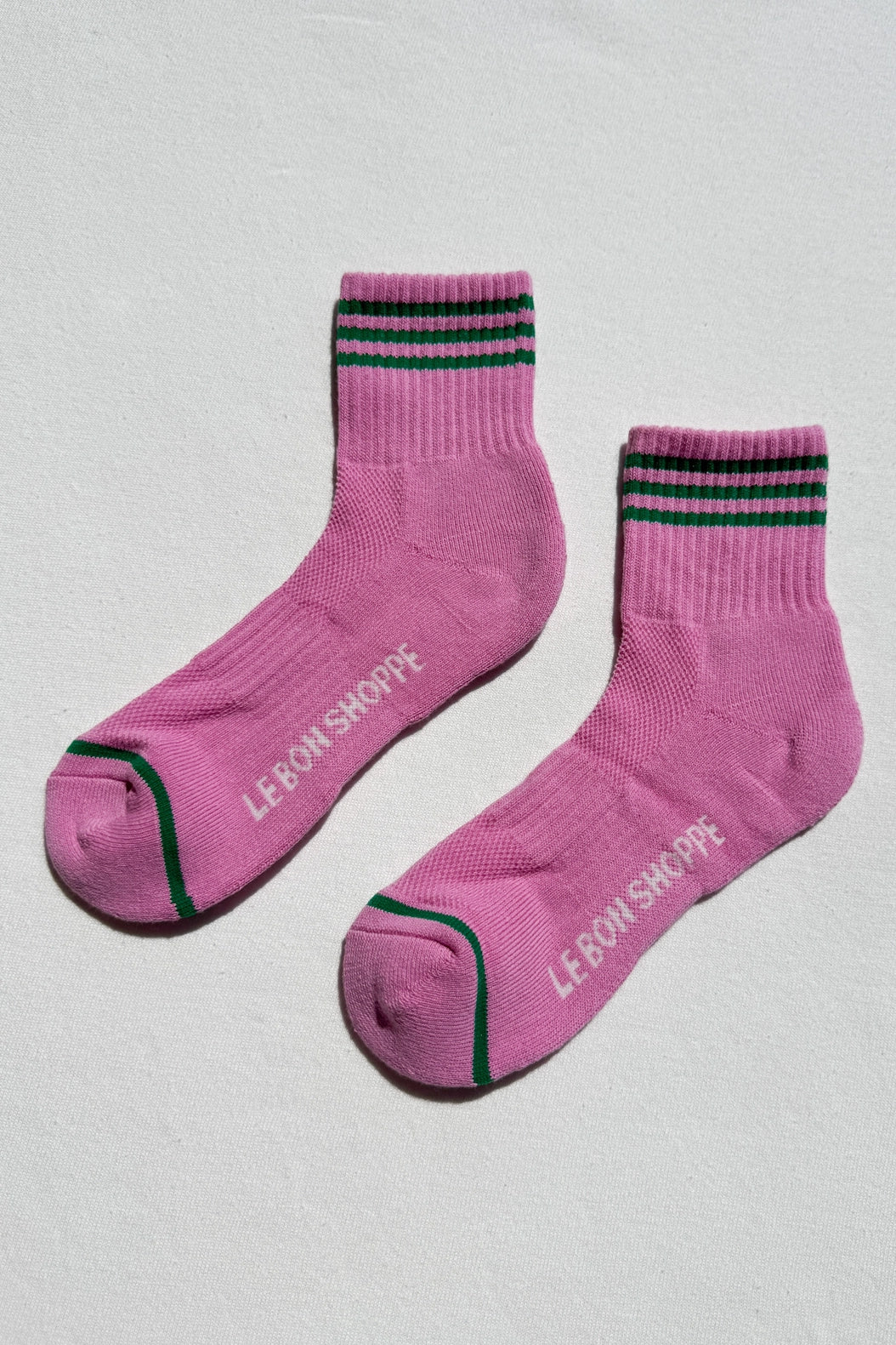 Pink socks with black and green accents on a light gray background