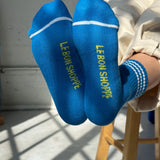 Bottom of peron's feet wearing blue socks with yellow Le Bon Shoppe branding