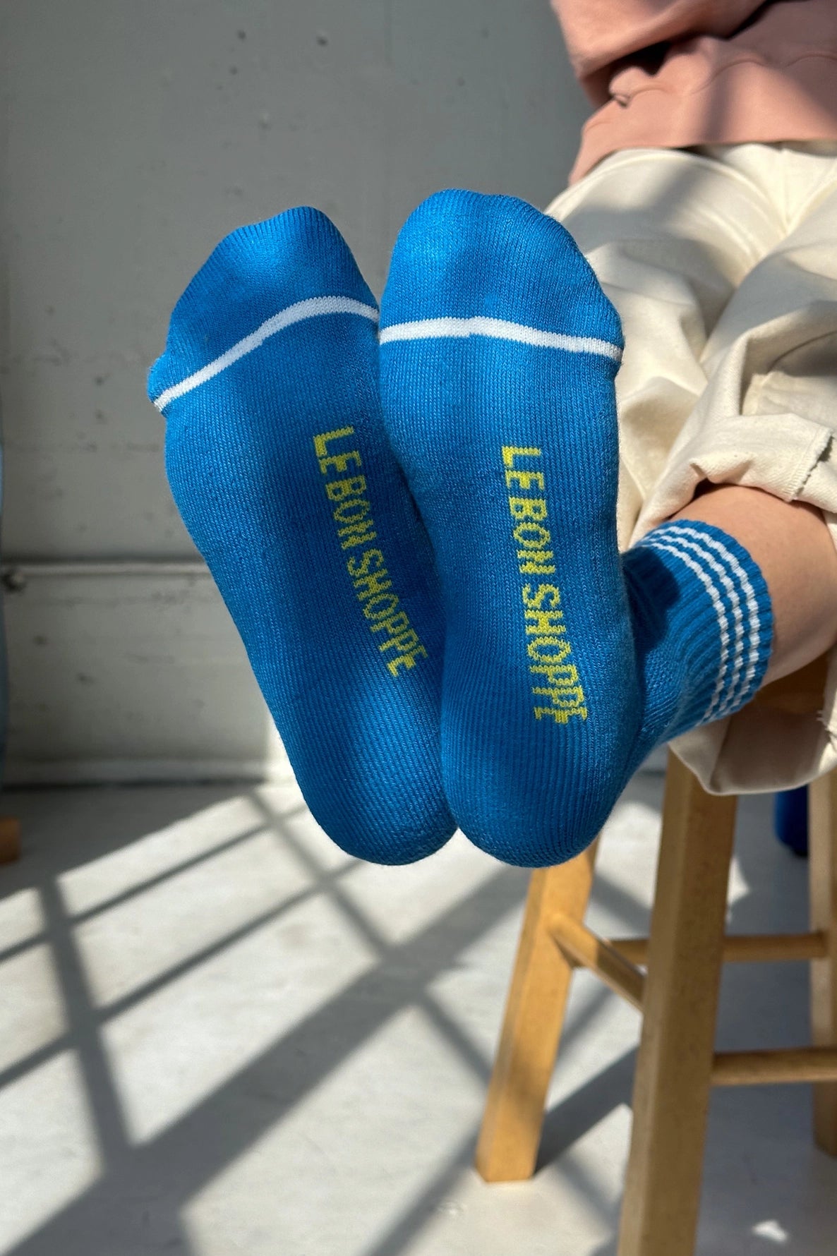 Bottom of peron's feet wearing blue socks with yellow Le Bon Shoppe branding