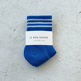 Blue socks with white stripes in whie Le Bon Shoppe packaging on light grey background