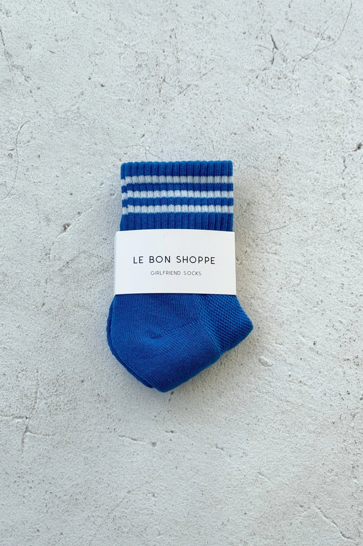 Blue socks with white stripes in whie Le Bon Shoppe packaging on light grey background