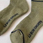 Pair of green socks with 'Le Bon Shoppe' branding on a white background