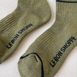 Pair of green socks with 'Le Bon Shoppe' branding on a white background