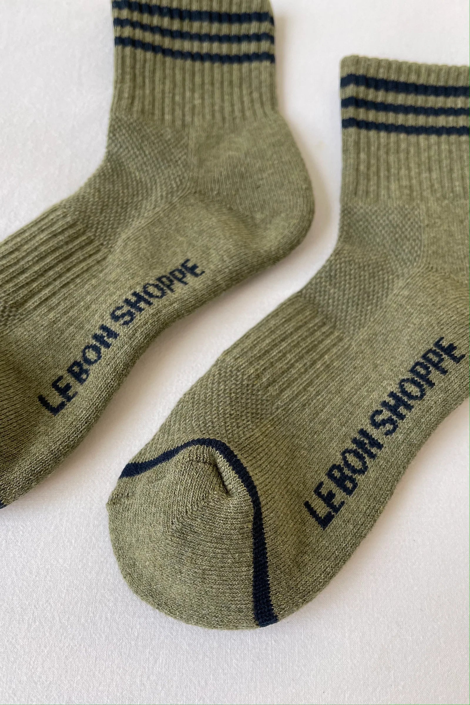 Pair of green socks with 'Le Bon Shoppe' branding on a white background
