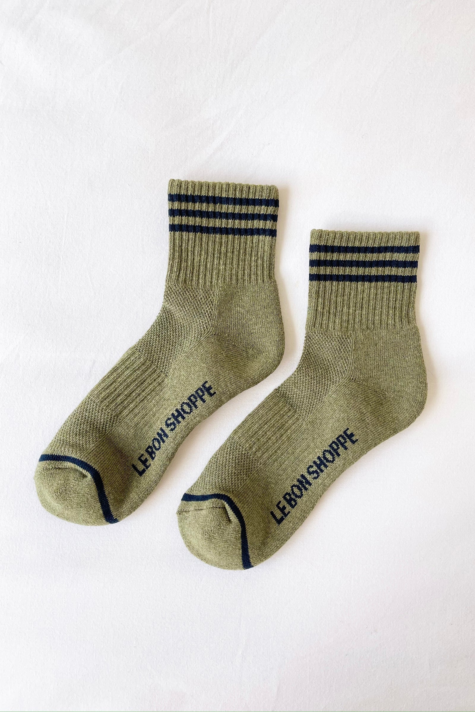 Pair of green socks with black stripes and 'LE BON SHOPPE' branding on a white background