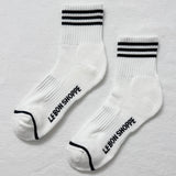 White socks with black stripes and 'LE BON SHOPPE' text on a light gray background