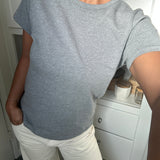 Person wearing a gray t-shirt and white pants in a room with a white cabinet.