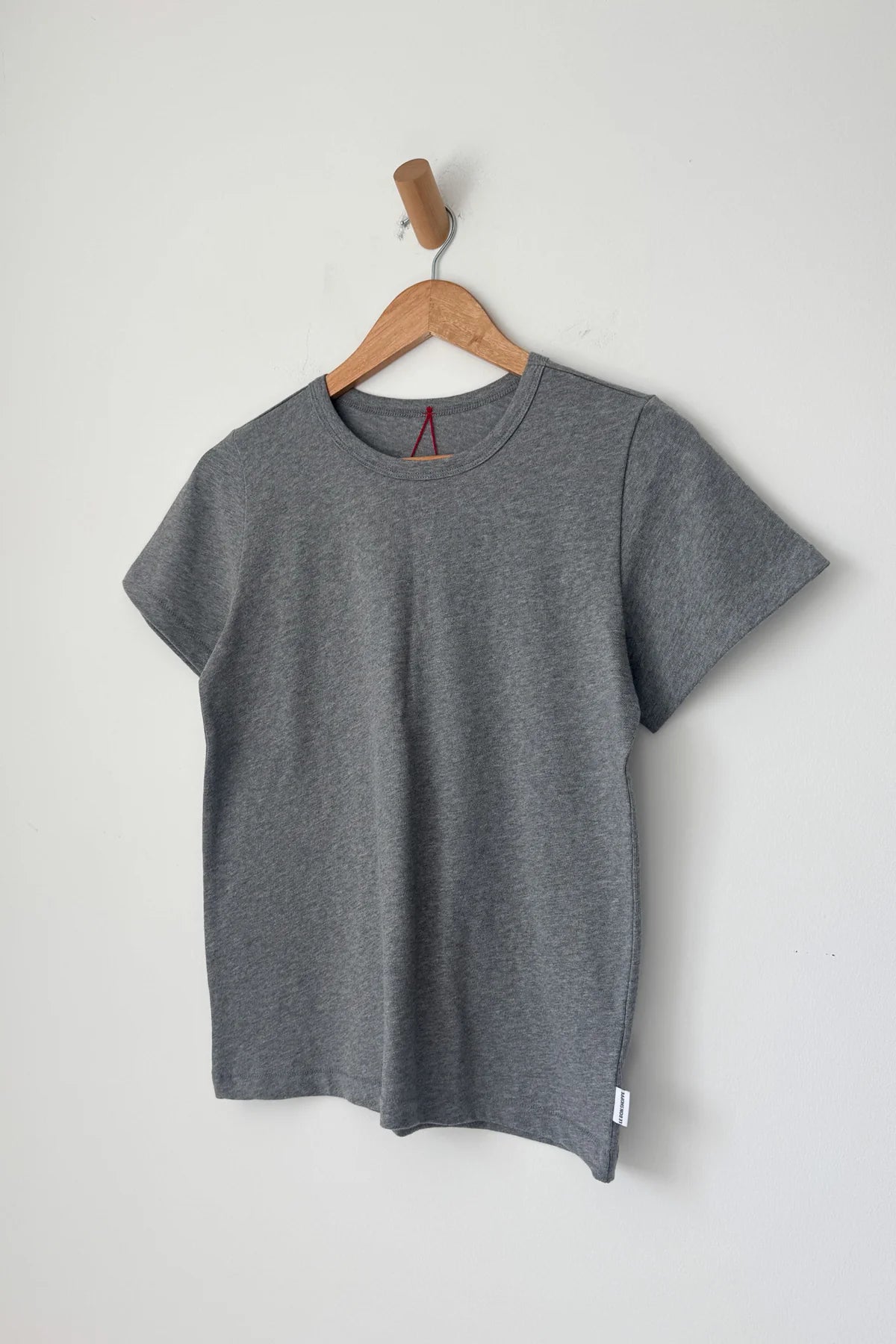 Gray t-shirt on a wooden hanger against a light gray background