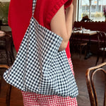 Person wearing a red outfit with a checkered bag in a restaurant setting