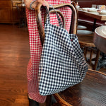 Person wearing a red checkered outfit with a black and white checkered bag in a restaurant setting