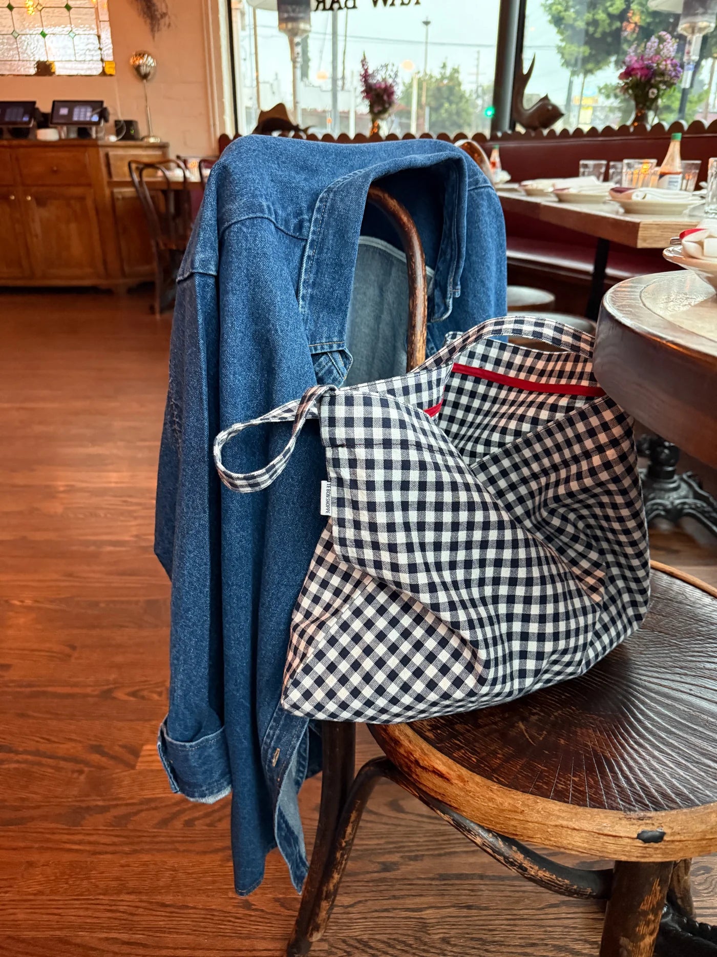 Blue denim jacket and checkered bag on a chair in a restaurant setting