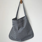 Black and white checkered bag hanging on a wooden hook against a white background