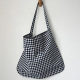 Black and white checkered bag hanging on a wooden hook against a white background