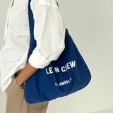 Person holding a blue bag with 'LE BON CREW' branding against a white background