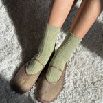 Person wearing green socks and brown shoes on a textured surface