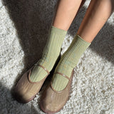 Person wearing green socks and brown shoes on a textured surface