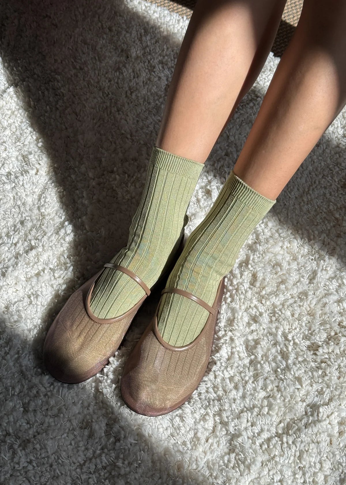 Person wearing green socks and brown shoes on a textured surface