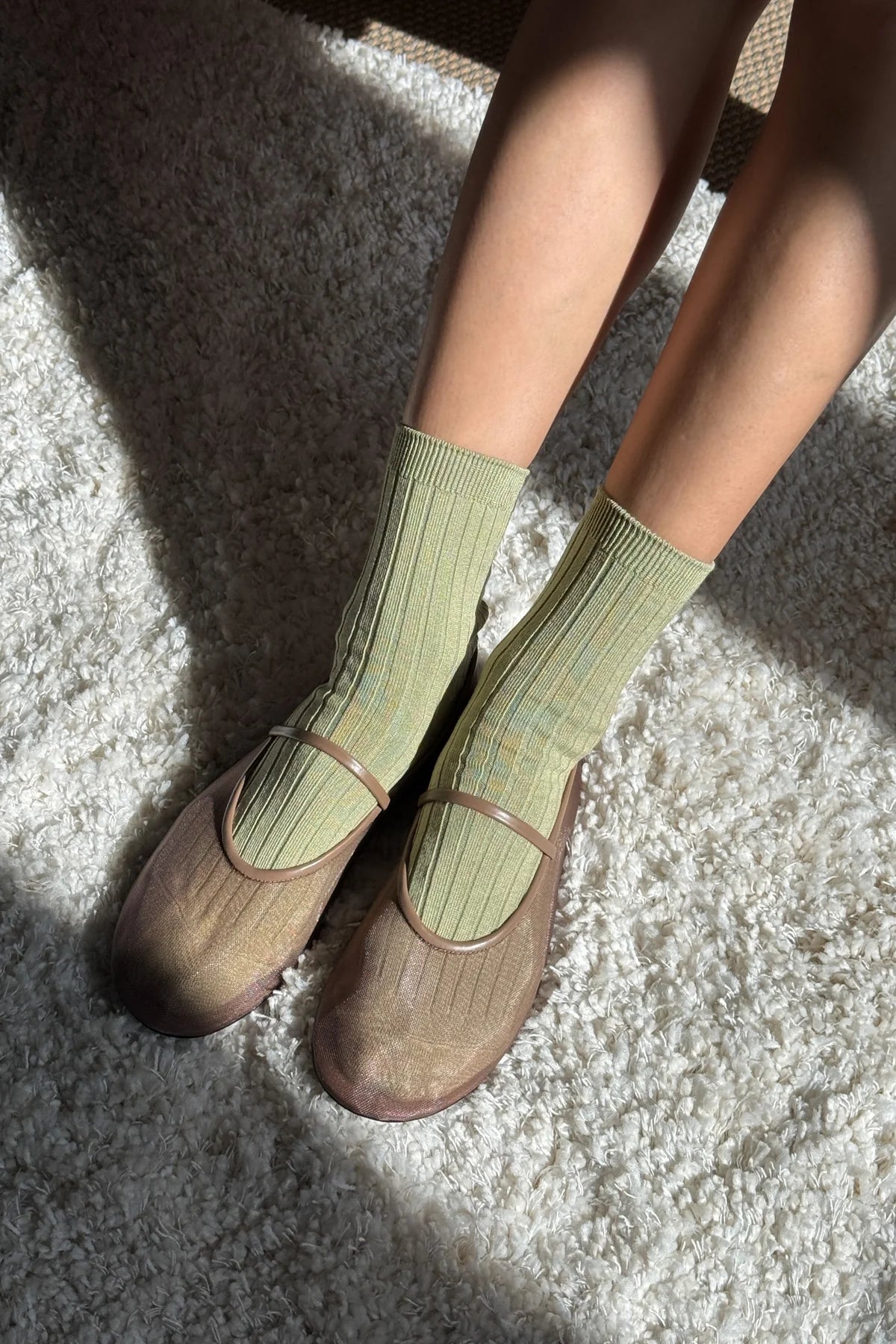 Person wearing green socks and brown shoes on a textured surface