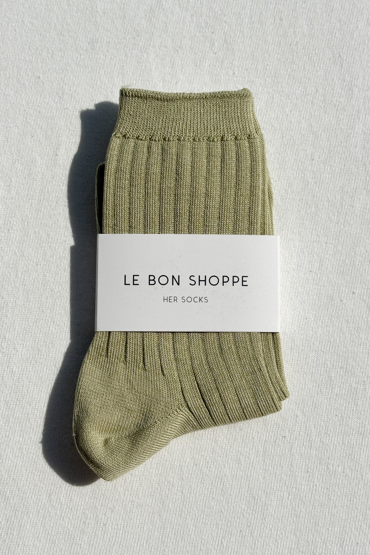 Green sock with a white label on a light gray background
