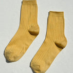 Pair of mustard yellow socks on a light gray background
