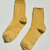 Pair of mustard yellow socks on a light gray background