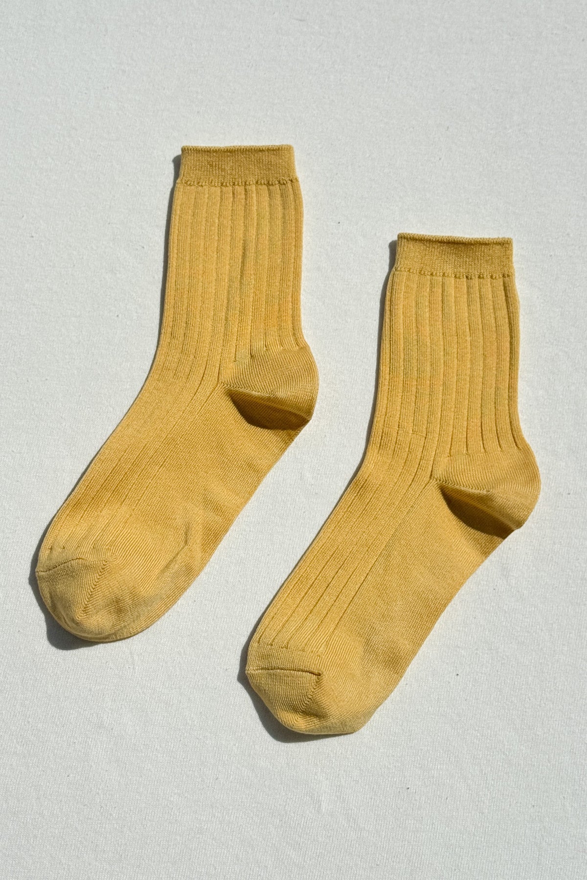 Pair of mustard yellow socks on a light gray background